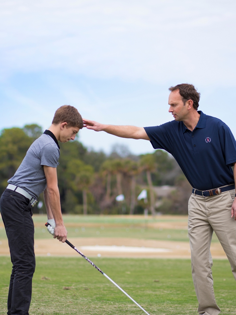 Teenager learning golf from an instructor